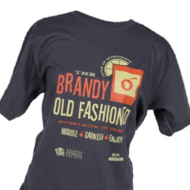 Frontside of a dark gray crew-cut t-shirt with an orange and yellow design and font. A yellow lemon slice sits on the lip of an orange, short cocktail glass with a cherry shaped like Wisconsin. The print says "The Brandy Old Fashioned", underneath: "Sweet Sour or Press", underneath: "Muddle. Garnish. Enjoy."