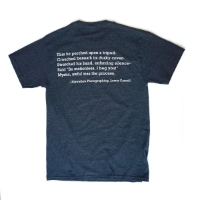 Backside of a crewcut charcoal gray t-shirt. Contains the text: 'This he perched upon a tripod-; Crouched beneath its dusky cover-; Stretch his hand, enforcing silence-; Said "Be motionless, I beg you!"; Mystic, awful was the process.' -Hiawatha's Photography, Lewis Carroll