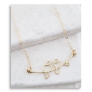 Gold love bird necklace featuring two birds sitting across branch. In front of white background.