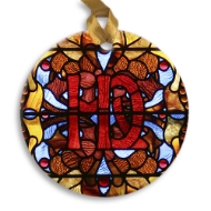 Round holiday ornament with a stained glass window design from Villa Louis historic site. Red, blue, orange.