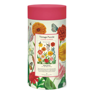 Back of the canister holding 1000 piece Flower Garden puzzle. The canister has a red lid and the back of the canister has a small illustration of the finished puzzle and details like size (22x28 inches).