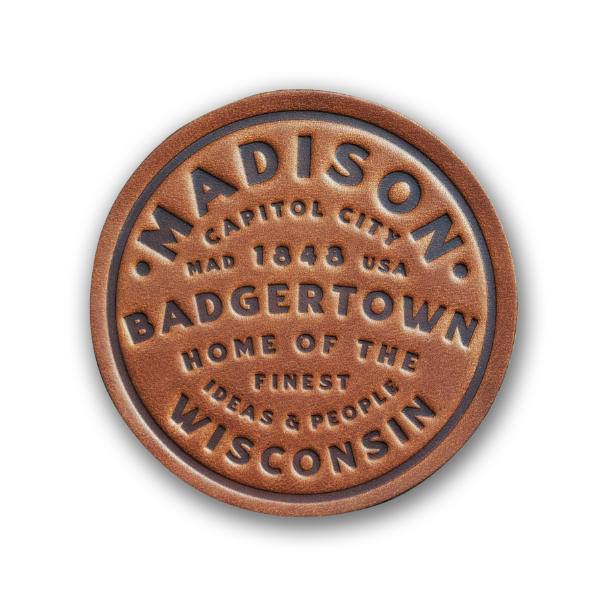 Round leather beverage coaster, medium brown, embossed with the words "Madison, Badgertown, Wisconsin" and more.