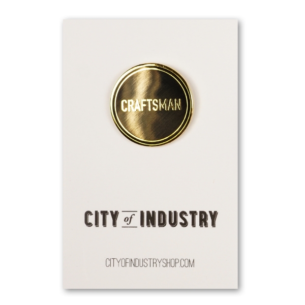 Round metal lapel pin that says "CRAFTSMAN" in raised chrome letters. Gold-tone chrome with black enamel.