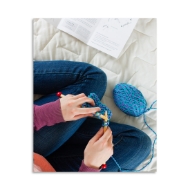 Overhead view of young person knitting with blue yarn. 