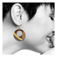 Profile view of woman wearing the brown, circular, earring with "March Balloons" motif from Frank Lloyd Wright. 