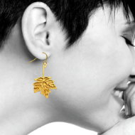 One brass maple leaf earring with gold electroplate and shepherd hook pictured here on woman's right ear. 