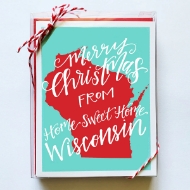 "Merry Christmas From Home Sweet Home Wisconsin" card on box with red and white twine holding in corners.