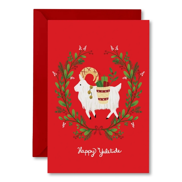 Red Yuletide card with red envelope. The red card has an illustration of a white goat encircled by a twig with green leaves.