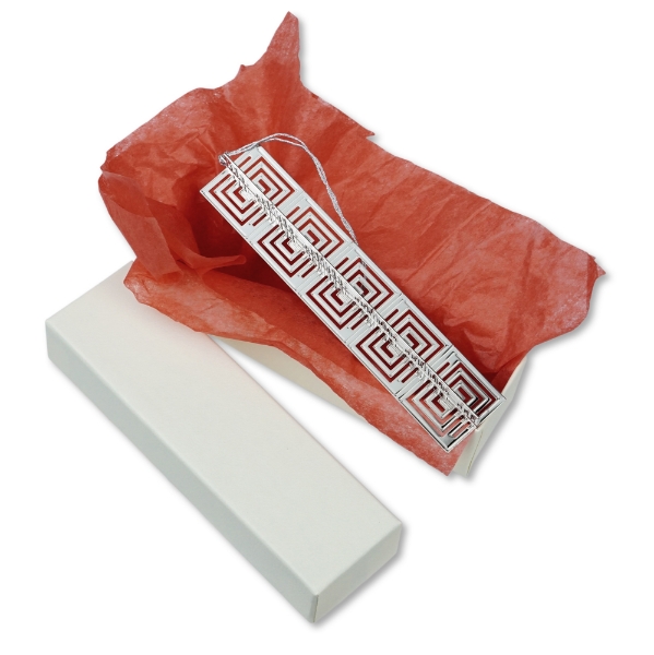 Frank Lloyd Wright 3D Whirling Arrow ornament with open package to display polished metal ornament set on red tissue paper.  
