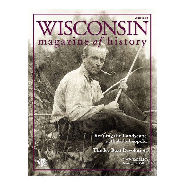 Cover of Wisconsin Magazine of History Winter 2020 edition. Sepia tone image of Aldo Leopold seated in natural setting smoking a pipe, wearing a bow tie.