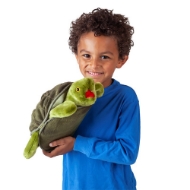 Child in blue shirt holding green, fabric, stuffed plush turtle puppet with domed "shell" and open red mouth.
