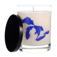 Great Lakes Candle in cylindrical clear glass with white wax and a white wick. The great lakes are shaded in blue. The black cover is resting on the side. 