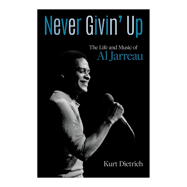 Book cover of "Never Givin' Up: The Life and Music of Al Jarreau" Featuring black and white photo of Jarreau holding a microphone.