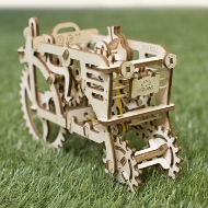 Unpainted, wooden model of a tractor with small, laser cut wooden parts. Made by Ugears. A 3/4 angle view with tractor model in grass.