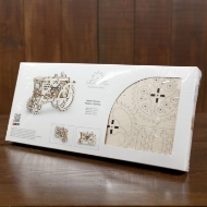 Box for wooden model of a tractor with small, laser cut wooden parts. Made by Ugears. The box rests on a brown wooden table.