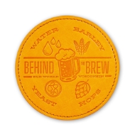 One circular leather coaster, orange. with embosed text and imagery about beer and Old World Wisconsin's "Behind the Brew" experience.