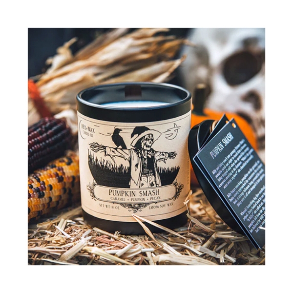 "Pumpkin Smash" candle with product positioned on hay with dried corn in background, a fall setting.