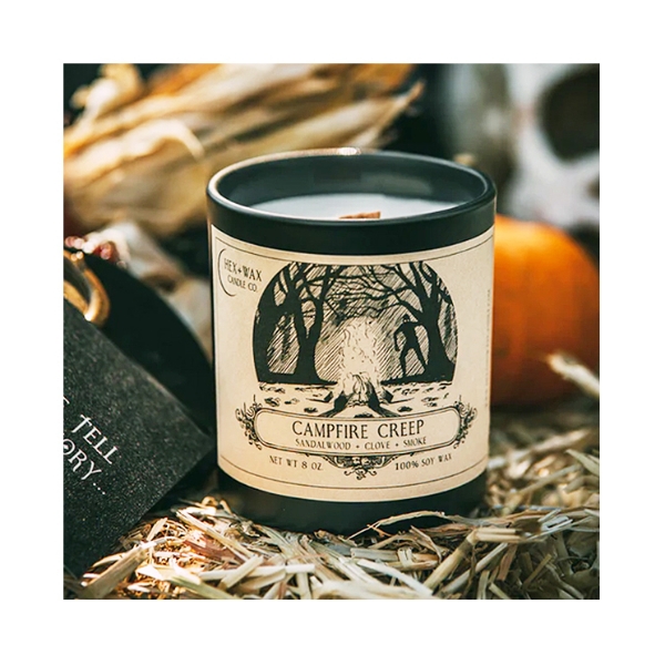 "Campfire Creep" candle with product positioned on hay with dried corn in background, a fall setting.