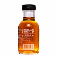 Small glass bottle of golden maple syrup. Side of bottle showing some nutritional components. 