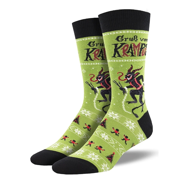 Two green socks with Krampus illustrations, white snowflakes, and Christmas trees on the side. Black toe, heel cap, and cuff.