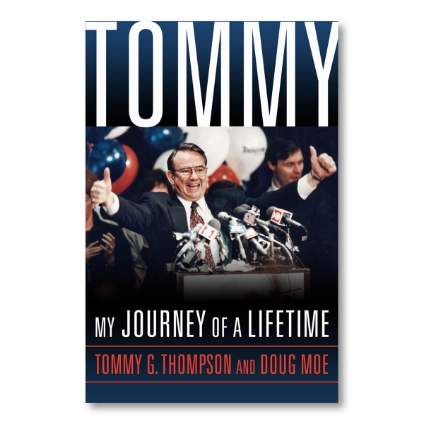 At the top of the cover, in large white letters, "TOMMY" is written on a dark blue background. Below that, there is a photograph of Tommy G. Thompson at a podium giving the thumbs up gesture. Under the photograph, the subtitle "MY JOURNEY OF A LIFETIME" is written in white text. Below the subtitle, the author's names, "TOMMY G THOMPSON AND DOUG MOE" are written in red.