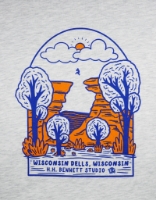 Close-up image of light gray t-shirt with blue and orange illustration of a figure leaping from one tall rock formation to another. The words "Wisconsin Dells, Wisconsin" below the illustration.