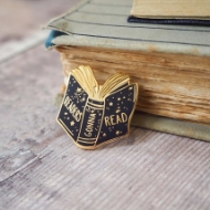 "Readers Gonna Read" Bookish Enamel Pin propped against a book