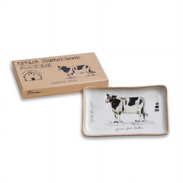 White butter dish with black and white cow illustration. Shown with its packaging. 