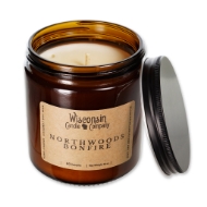 The Northwoods Bonfire 16 oz candle in brown glass container, open, with black metal screw-on lid leaning on side of jar.