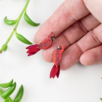 The Red Cardinal Stud Earrings held in someone's hand